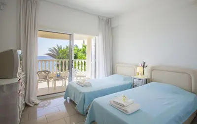 a hotel room with two beds and a balcony at Meneou Beachfront Villa Sunset in Pervolia