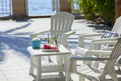 three white chairs and a table with plants on it at Meneou Beachfront Villa Sunset in Pervolia