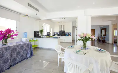 a dining room with a table and chairs and a kitchen at Meneou Beachfront Villa Sunset in Pervolia