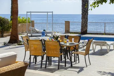 a table and chairs with the ocean in the background at Meneou Beachfront Villa Sunset in Pervolia