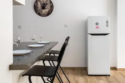 a table with chairs and a refrigerator in a room at Levante - 2-BR Apt & Terrace in Larnaca in Larnaka