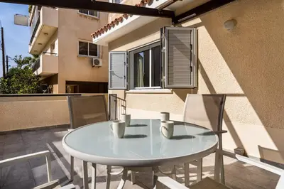 a glass table and chairs on the balcony of a building at Levante - 2-BR Apt & Terrace in Larnaca in Larnaka