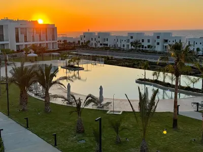 a resort with a pool with palm trees and a sunset at CoveDream Studio Sun Valley Esentepe in Aglantzia