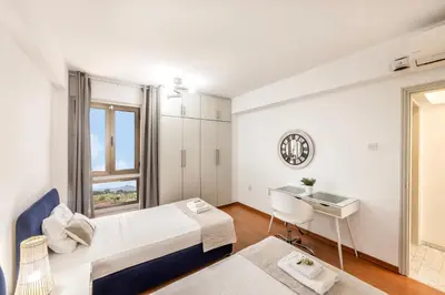 a bedroom with a bed and a desk and a window at Mackenzie Beachfront Suite in Larnaka