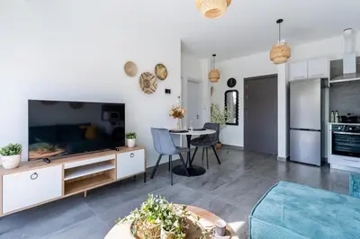a living room with a large television and a table at Azoria - Stylish 1-BR Apartment & Balcony in Kiti in Kiti