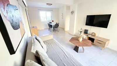 a living room with a couch and a tv and a table at 2BR Apartment with Pool & Free Wi-Fi in Larnaka