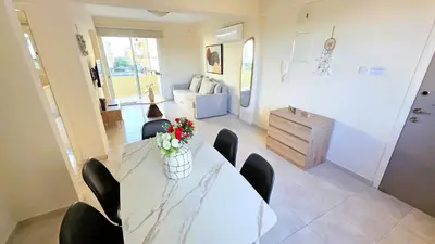 a living room with a white table and chairs at 2BR Apartment with Pool & Free Wi-Fi in Larnaka