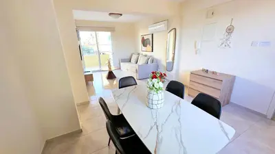 a living room with a dining room table and chairs at 2BR Apartment with Pool & Free Wi-Fi in Larnaka