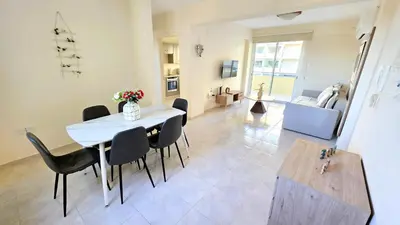 a dining room and living room with a table and chairs at 2BR Apartment with Pool & Free Wi-Fi in Larnaka
