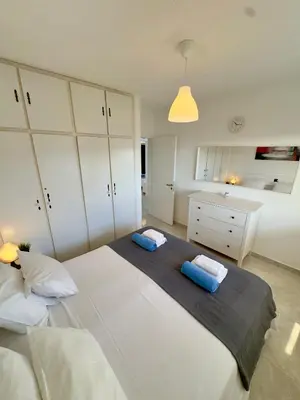 a bedroom with a large white bed with two blue pillows at Napa Skyline Suite 3BR Sunset Views and Pool in Ayia Napa