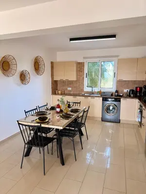 a dining room with a table and chairs in a kitchen at Rope and Reef 2BD Walk to Nissi Beach and Pool in Ayia Napa
