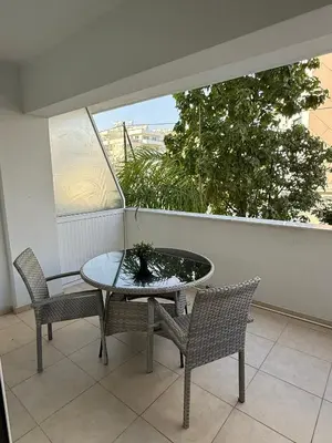 a table and chairs on a balcony with a window at Blue Edge Makenzy in Larnaka