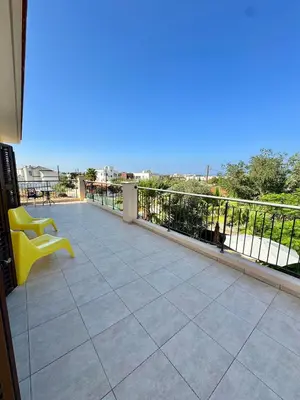 a balcony with a yellow chair sitting on top of it at Aurora Gardens Villa Spacious 3 Bedroom in Protaras in Paralimni