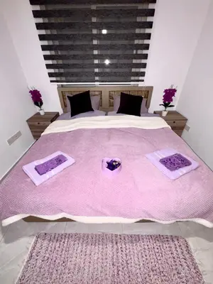 a bedroom with a large bed with two purple mats on it at Lapta Purple 2 bedroom in Peristerona