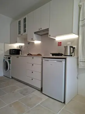 a kitchen with white cabinets and a washer and dryer at Cecilia Traditional House-Suites in Kalopanayiotis