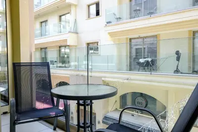 a table and chairs on a balcony with a building at Downtown 2 Bedroom City Flat in Larnaka