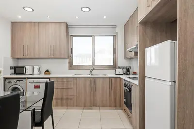 a kitchen with wooden cabinets and a white refrigerator at Downtown 2 Bedroom City Flat in Larnaka