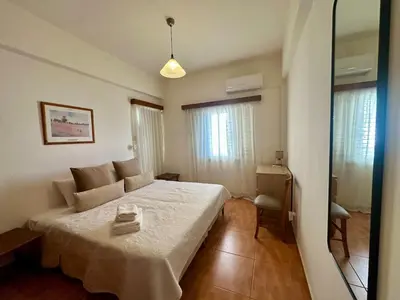 a bedroom with a large bed and a room with windows at 2 bedroom flat by the sea in Larnaka