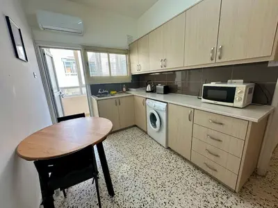 a small kitchen with a table and a microwave at 2 bedroom flat by the sea in Larnaka