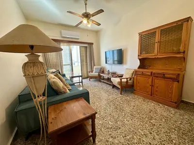 a living room with a green couch and a ceiling fan at 2 bedroom flat by the sea in Larnaka