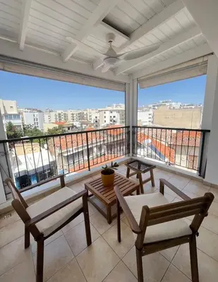 a balcony with chairs and tables and a large window at 2 bedroom flat in centre in Larnaka