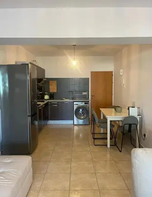a small kitchen with a table and a refrigerator at 2 bedroom flat in centre in Larnaka