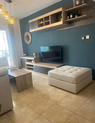 a living room with a white ottoman and a television at 2 bedroom flat in centre in Larnaka