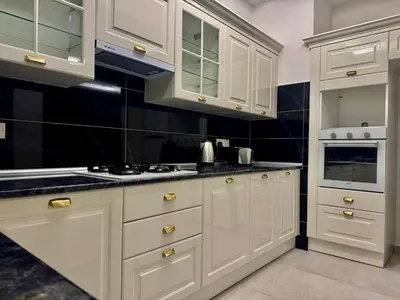 a kitchen with white cabinets and a black wall at Soğular Apartments 1 in Aglantzia
