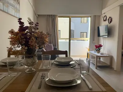 a dining room table with plates and a vase of flowers at One-bedroom apartment next to Radisson Blu in Larnaka