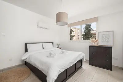 a white bedroom with a large bed and a window at Downtown Stadium 3 Bedroom Apartment in Larnaka
