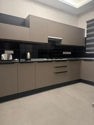 a kitchen with white cabinets and black appliances at Soğular Apartments 1 in Aglantzia