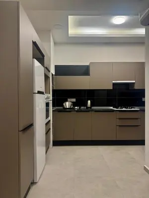 a kitchen with brown cabinets and a white refrigerator at Soğular Apartments 1 in Aglantzia