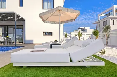 a patio with white furniture and an umbrella at Villa Elizabeth - Pernera Resort Center in Paralimni