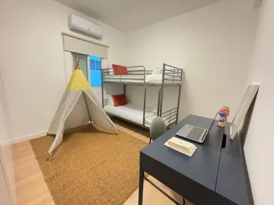 a room with a desk and a bed and a table with a laptop at GameHouse in the City Center in Nicosia
