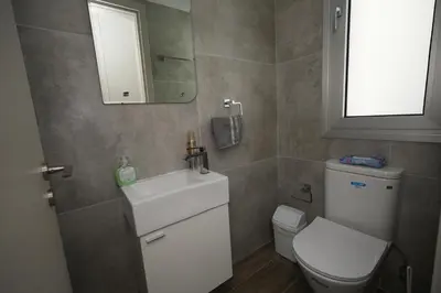 a bathroom with a toilet and a sink and a mirror at Larnaca Salt Lake Gem, Airy 2 BDRM Apartment in Larnaka