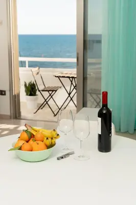 a table with a bowl of fruit and two wine glasses at Stunning Mackenzie Sea Views Beach Flat,1 Bedroom in Larnaka