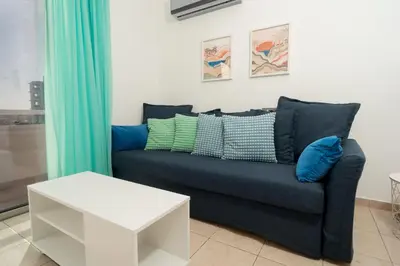 a living room with a blue couch and a table at Stunning Mackenzie Sea Views Beach Flat,1 Bedroom in Larnaka