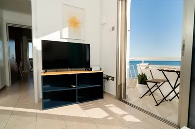 a living room with a television and a view of the ocean at Stunning Mackenzie Sea Views Beach Flat,1 Bedroom in Larnaka