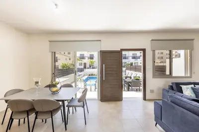 a living room with a table and a blue couch at SunnyVillas 3BR House Private Pool POLY in Protaras