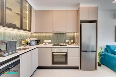 a kitchen with white cabinets and a refrigerator at Lordos Deluxe 2bd Duplex with pool and Seaview in Larnaka