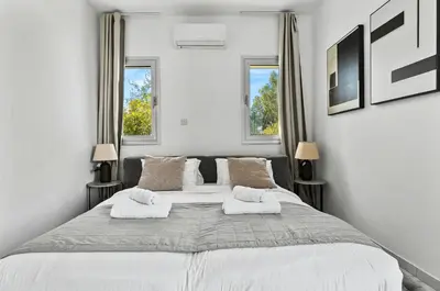 a white bedroom with a large bed with two pillows at STYLE Limassol by Ezoria Villas in Limassol