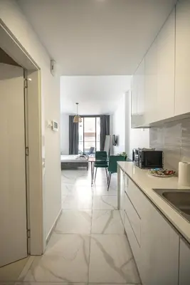 a kitchen with white cabinets and a living room at Mackenzie Signature Studio Suite in Larnaca in Larnaka