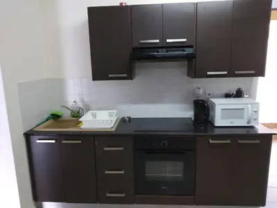 a kitchen with brown cabinets and a white microwave at 2br-7 Guests-Free Parking-Pool-AirCon in Paralimni