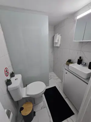 a white bathroom with a toilet and a sink at Marble Coast Studio Apartment in Larnaka