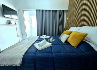 a bedroom with a blue bed with yellow pillows at Marble Coast Studio Apartment in Larnaka