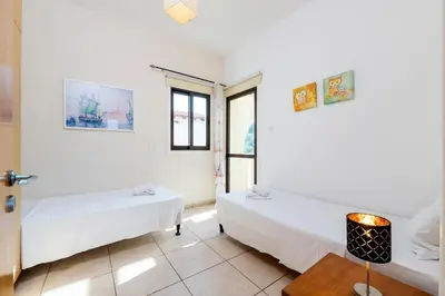 a white room with two beds and a table at Sunnyside Family Villa in Protaras