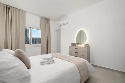 a white bedroom with a bed and a mirror at Mnasiadou Suite 16 in Nicosia