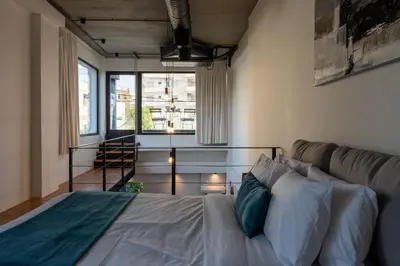 a bedroom with a bed and a couch and a window at Cozy Loft with Balcony in Central Limassol in Limassol