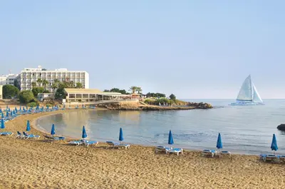 a beach with chairs and umbrellas and a sail boat at Villa Elsa - Luxury Villa in Pernera in Paralimni