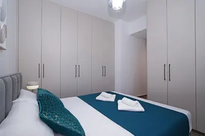 a bedroom with a bed with white cabinets and blue sheets at Villa Esmeralda - Luxury Villa in Pernera in Paralimni